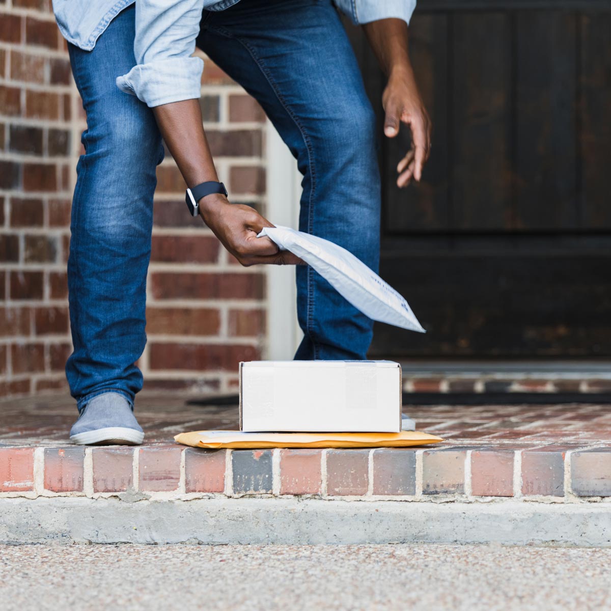 Person picking up mail from their porch